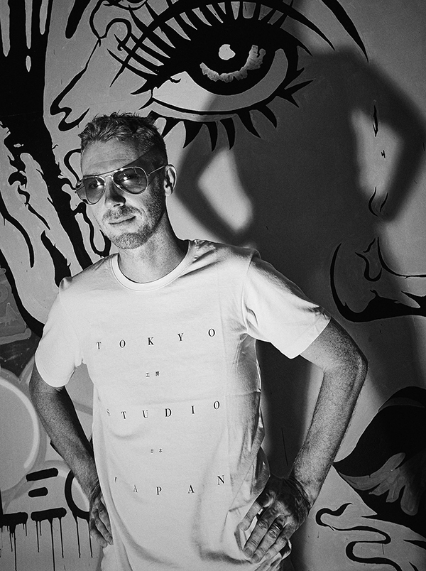 A black-and-white photo of a man wearing glasses and a t-shirt with 