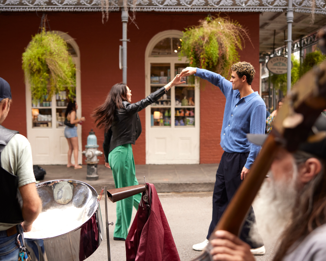 A joyful moment on a lively street, where a man and woman joyfully high-five each other. background features musicians and passersby near a building with hanging plants.