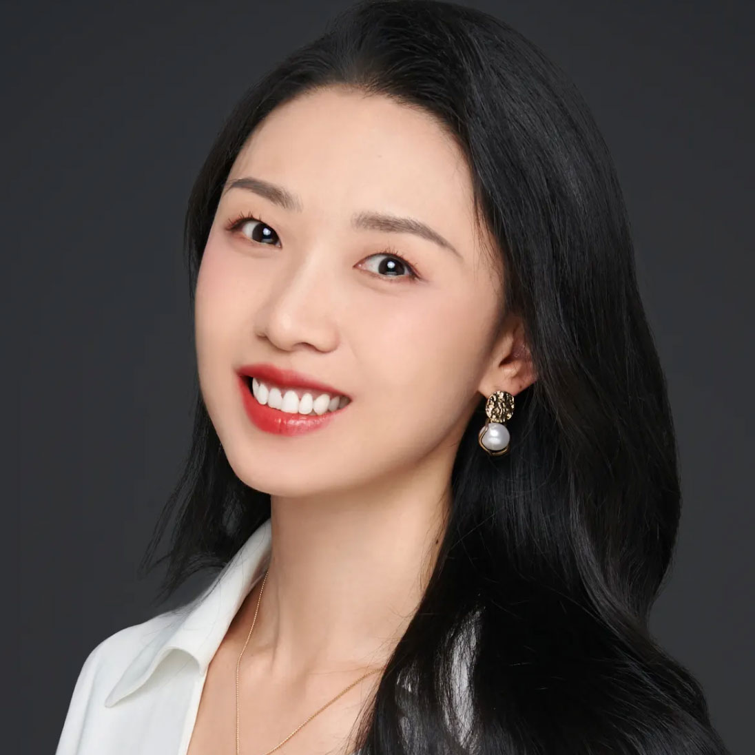 A woman with long black hair and a pearl earrings.