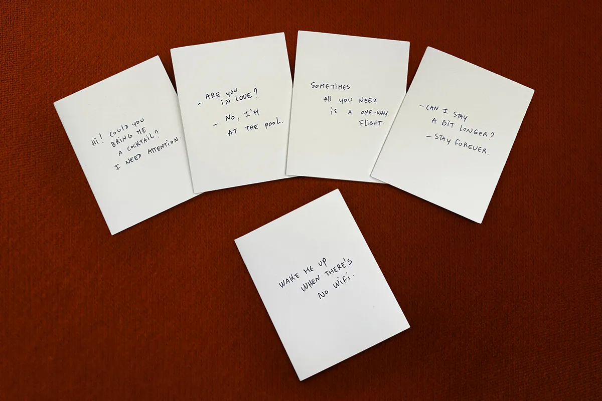 Five white cards with handwritten messages are laid out on an orange surface. The messages say: 