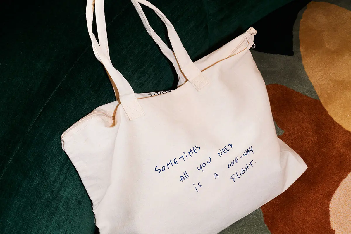 Una bolsa de mano de color crema con un texto escrito a mano en tinta azul que dice: 