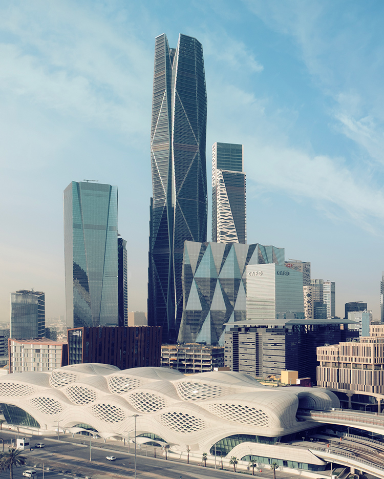 A cityscape featuring modern skyscrapers with unique geometric designs and a futuristic building with a honeycomb-patterned roof in the foreground, under a partly cloudy blue sky.